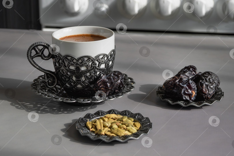 Скачать Чашка кофе стоит рядом с сушеными финиками и семенами кардамона. фотосток Ozero