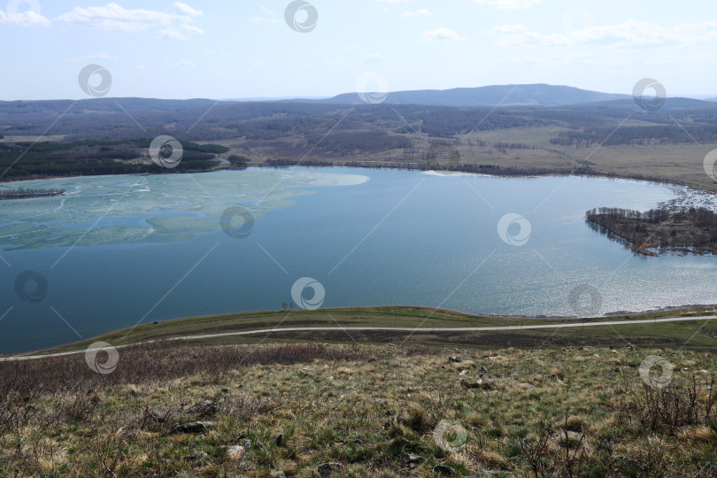 Скачать весеннее таяние льда на озере, дорога вдоль пруда и остров, покрытый лесом фотосток Ozero