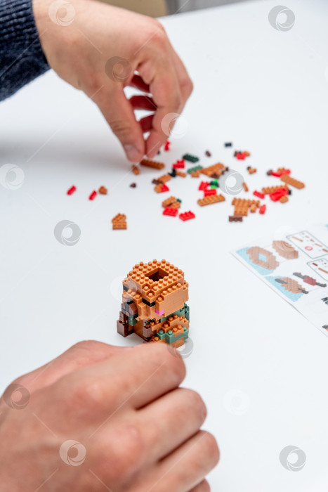 Скачать Бар, Черногория, 20 марта 2026 года, Мужчина играет в конструктор Lego с фигуркой животного капибары фотосток Ozero
