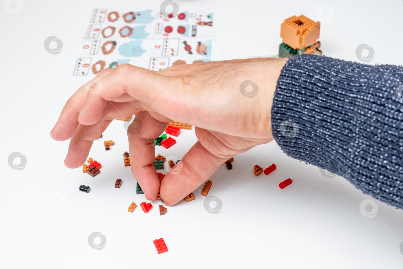 Скачать Бар, Черногория, 20 марта 2026 года, Мужчина играет в конструктор Lego с фигуркой животного капибары фотосток Ozero