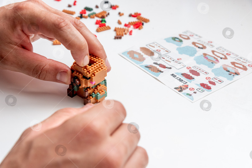 Скачать Бар, Черногория, 20 марта 2026 года, Мужчина играет в конструктор Lego с фигуркой животного капибары фотосток Ozero