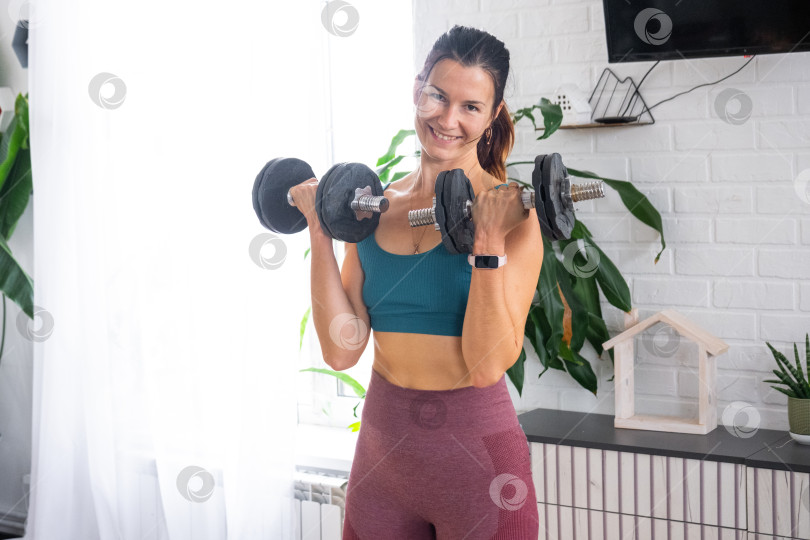 Скачать Женщина, тренирующаяся с отягощениями дома, спортивный образ, минимум шика, растительный декор в интерьере, саморазвитие, домашний велнес-центр, здоровый образ жизни фотосток Ozero