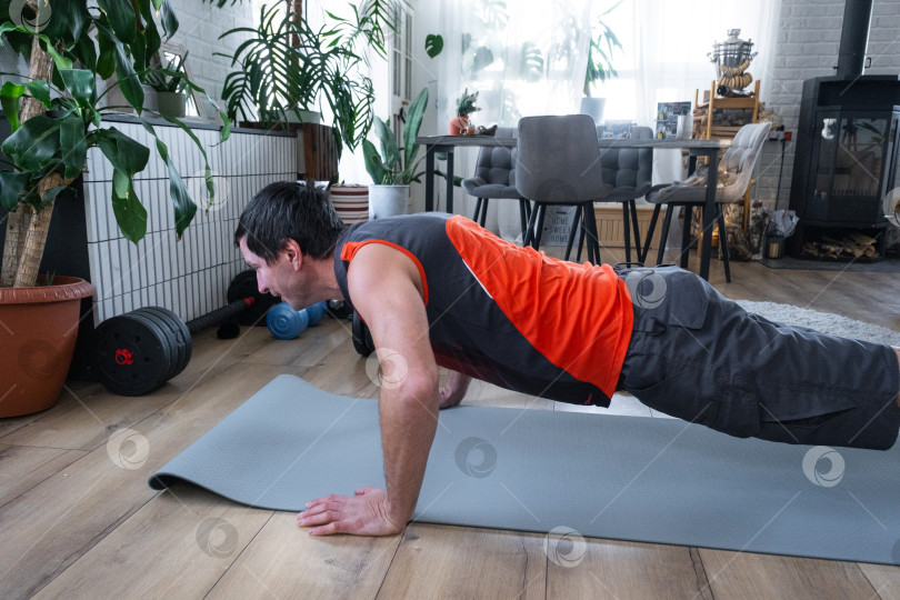 Скачать Мужчина отжимается на коврике, фитнес дома, спортивный топ, здоровый распорядок дня, светлая комната, растения, сильная самодисциплина, оздоровительная зона фотосток Ozero