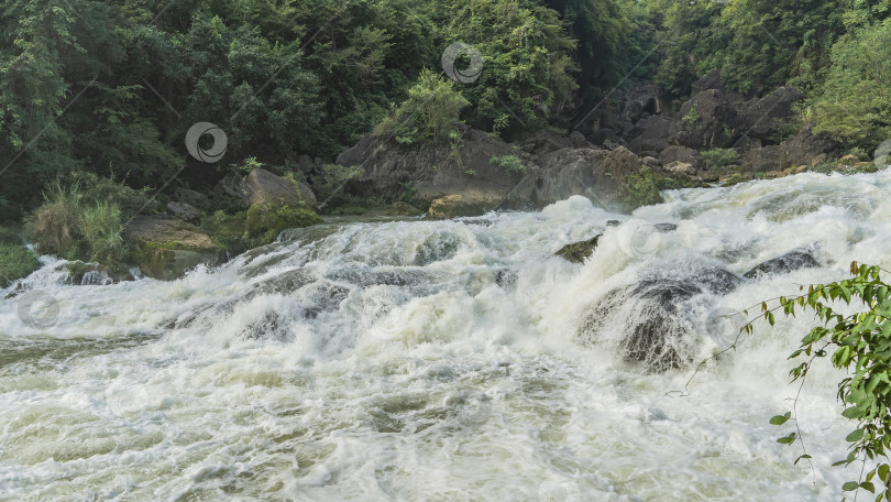 Скачать Горная река. Бурные потоки белой пены разбиваются о валуны в русле реки. фотосток Ozero