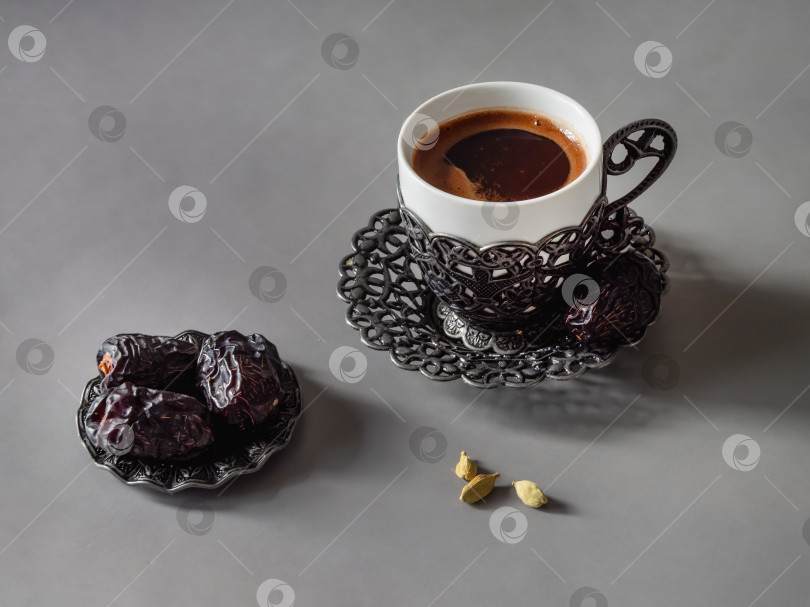 Скачать Чашка кофе стоит рядом с сушеными финиками и семенами кардамона. фотосток Ozero