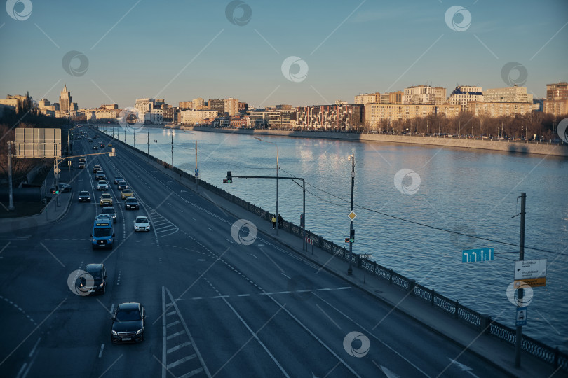 Скачать Москва, Россия, 22.03.26. Панорамный вид на Москву-реку и оживленную набережную в лучах закатного солнца. фотосток Ozero