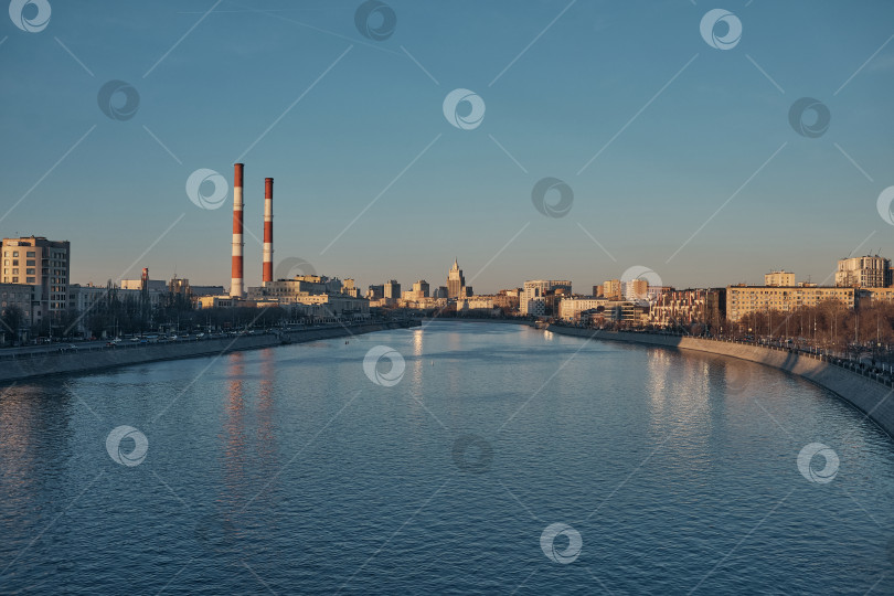 Скачать Широкая панорама Москвы-реки с видом на Бережковскую набережную и индустриальные трубы ТЭЦ на закате. фотосток Ozero