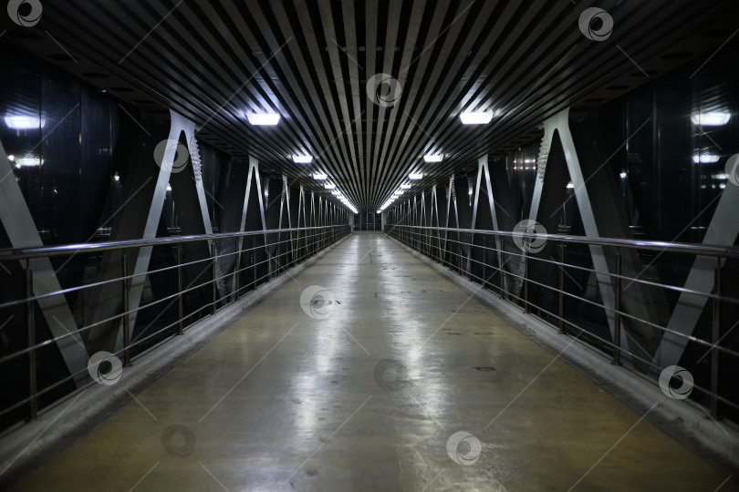 Скачать Москва, Россия, 22.03.2026. Современный футуристический пешеходный переход с симметричной перспективой и неоновым освещением ночью. фотосток Ozero