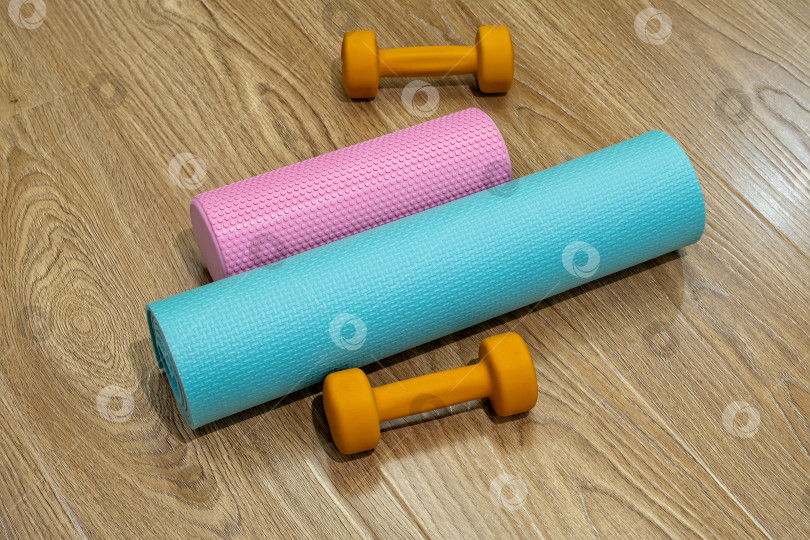 Скачать Коврики для йоги и гантели на деревянном полу, готовые к занятиям фитнесом в домашнем тренажерном зале в начале дня фотосток Ozero