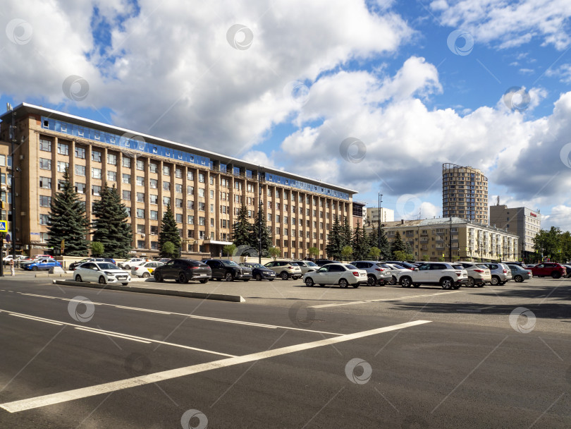 Скачать Вид на Октябрьскую площадь в Перми с Екатерининской улицы. Видны здание бизнес-центра, автостоянка на Октябрьской площади и жилые дома вдалеке. Летний городской пейзаж Перми. 30.07.2025 фотосток Ozero