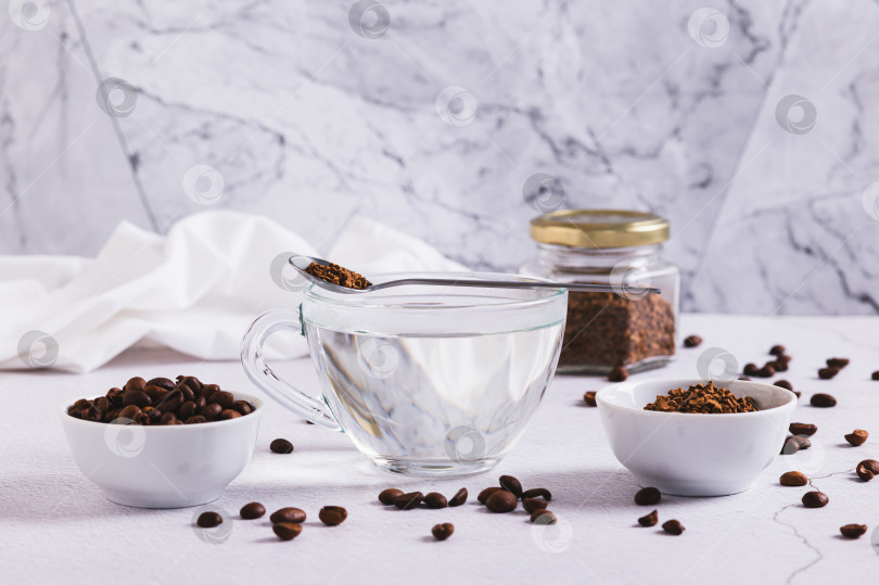 Скачать Чашка с водой, растворимый кофе в гранулах и кофейных зернах на столе фотосток Ozero