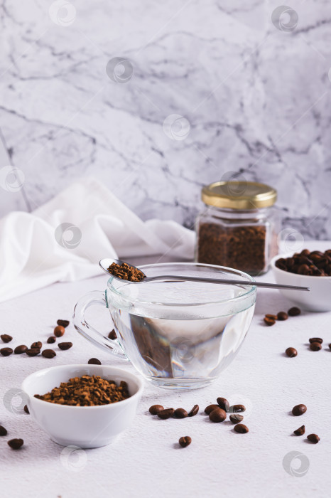 Скачать Чашка с водой, гранулы растворимого кофе и кофейные зерна на столе в вертикальном положении фотосток Ozero