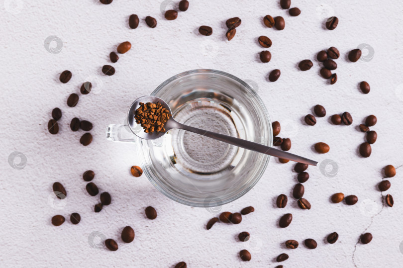 Скачать Крупный план чашки с водой, гранулами растворимого кофе и кофейными зернами на столе, вид сверху фотосток Ozero