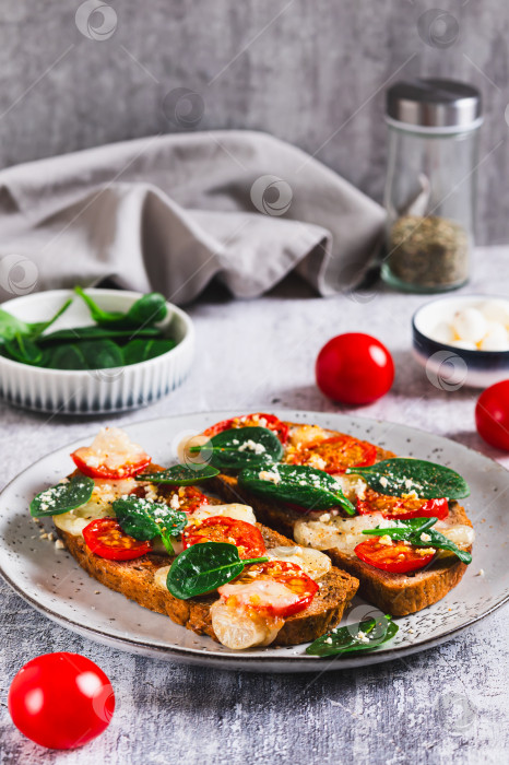 Скачать Запеченные бутерброды с моцареллой, помидорами и шпинатом на тарелке в вертикальном положении фотосток Ozero