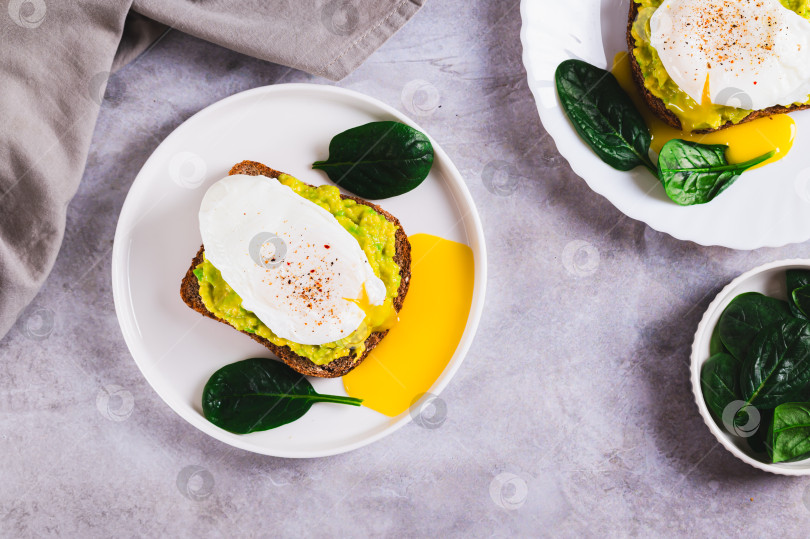 Скачать Ржаной хлеб с гуакамоле и яйцом-пашот на тарелке на столе вид сверху фотосток Ozero