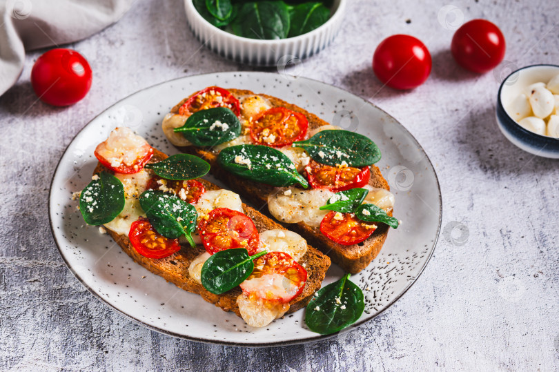 Скачать Запеченная брускетта с салатом капрезе и шпинатом на тарелке на столе фотосток Ozero
