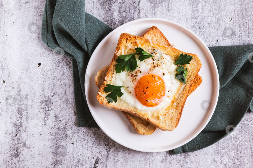 Скачать Крупный план яйца, запеченного в кусочках хлеба, на тарелке на столе, вид сверху фотосток Ozero