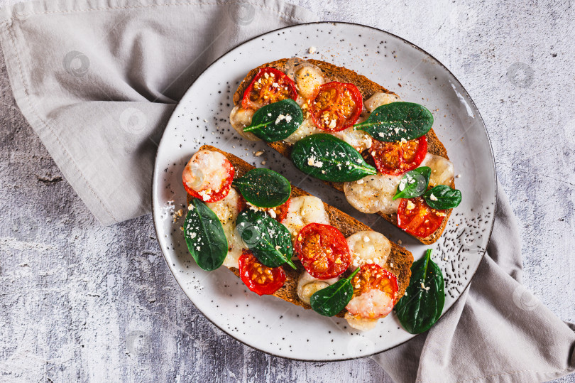 Скачать Выложите на тарелку горкой запеченные бутерброды с моцареллой, помидорами и шпинатом, вид сверху фотосток Ozero