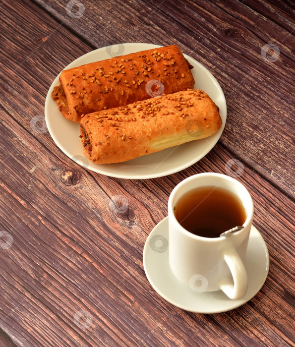 Скачать Чашка черного чая и тарелочка с двумя булочками, начиненными карамелью и посыпанными тертыми орехами. фотосток Ozero