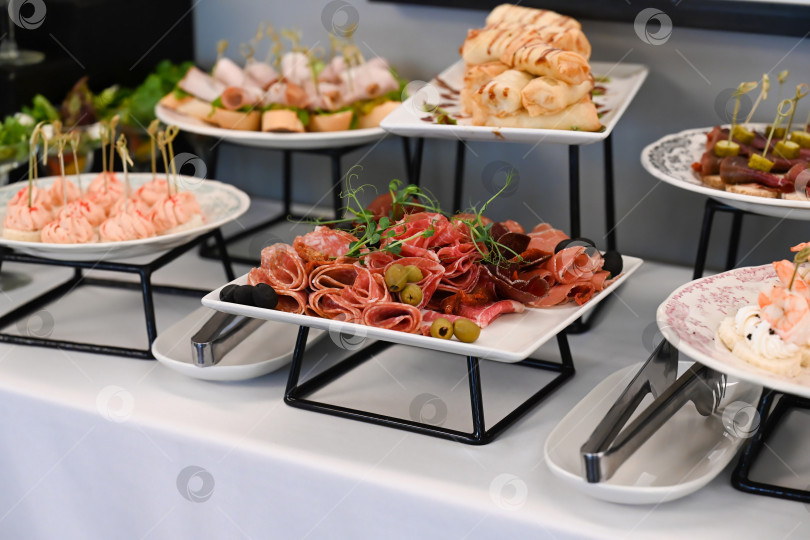 Скачать Разнообразная закуска для кейтеринга с мясным ассорти, салями и прошутто на фуршетном столе для украшения мероприятия или вечеринки в отсутствие людей и свободного пространства для копирования фотосток Ozero