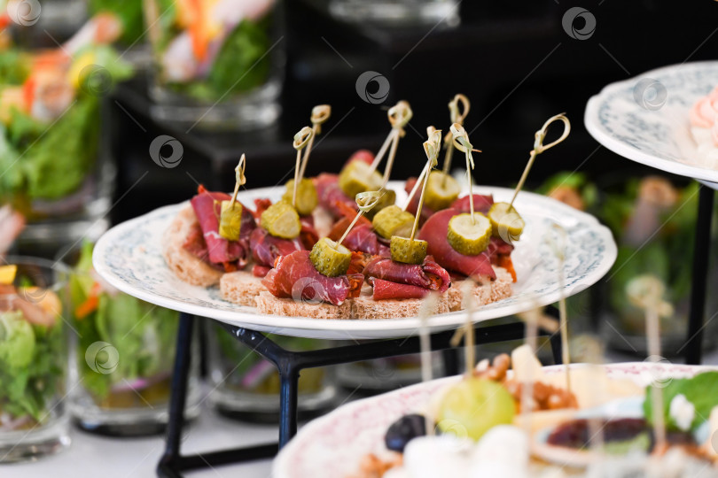 Скачать Разнообразная закуска для кейтеринга с канапе из говядины и корнишонами на шпажке для украшения мероприятия или вечеринки с вкусной пикантной мясной закуской на фуршетном столе фотосток Ozero
