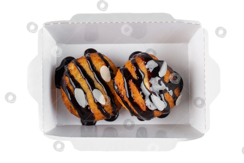 Скачать Сладкое заварное печенье с шоколадным соусом и миндальными хлопьями в белой бумажной коробке для выноса на белом фоне, вид сверху крупным планом, плоская обложка с пространством для копирования фотосток Ozero