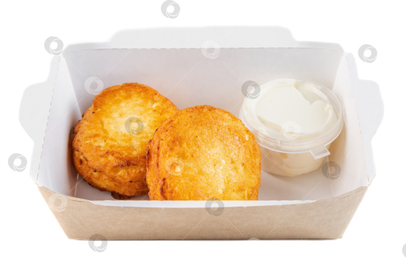 Скачать Хрустящие картофельные оладьи со сметанным кремом в картонной коробке на вынос на белом фоне вид сбоку крупным планом с возможностью копирования вкусный пикантный завтрак фотосток Ozero