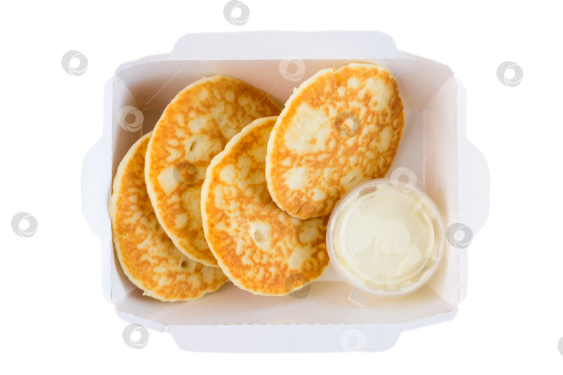 Скачать Сладкий толстый блинчик со сметанным кремом в белой бумажной коробочке на вынос на белом фоне вид сверху крупным планом на плоской поверхности с возможностью копирования вкусный завтрак фотосток Ozero