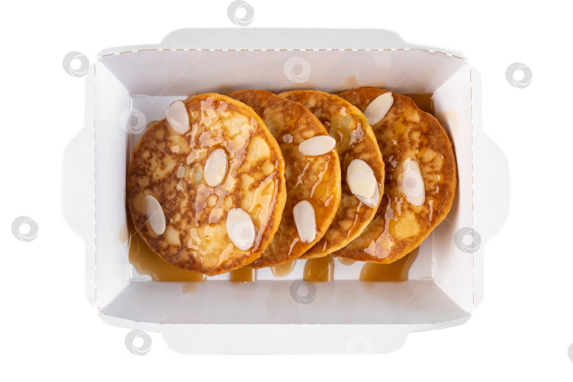Скачать Сладкие блинчики с сиропной начинкой и миндальными хлопьями в белой бумажной упаковке, которые можно вынимать из коробки, вид сверху крупным планом, на плоской поверхности, вкусные блюда для завтрака в одиночестве фотосток Ozero