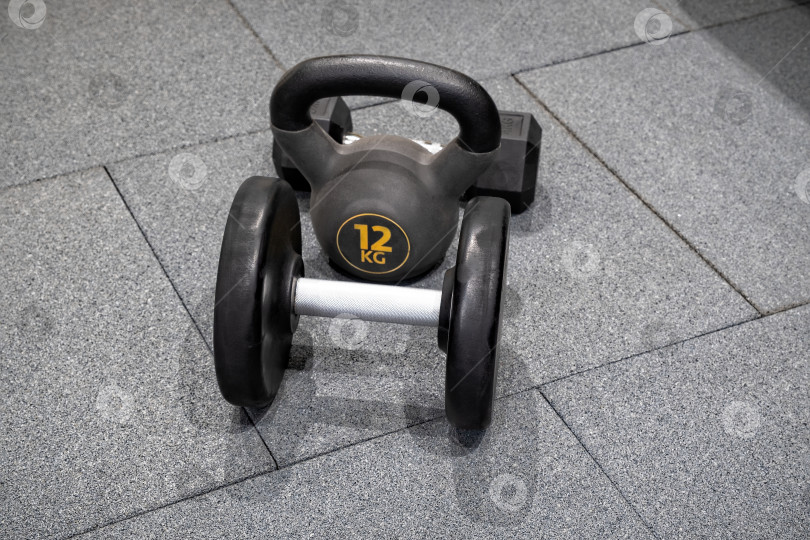 Скачать Гантели и гири, расставленные на полу тренажерного зала для занятий в фитнес-центре в дневное время фотосток Ozero