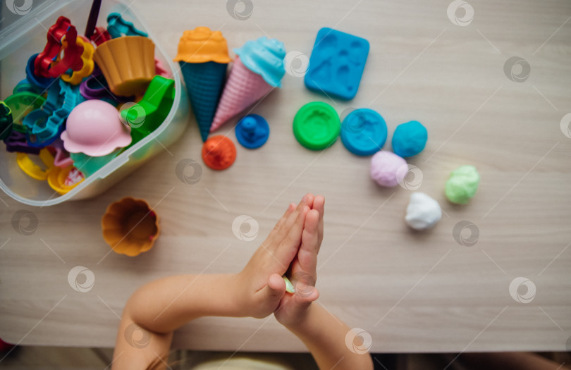 Скачать Маленькая девочка лепит фигурки из цветного воздушного пластилина, теста для лепки. Увлечения для детского творчества, развивающие занятия, развитие мелкой моторики рук. фотосток Ozero