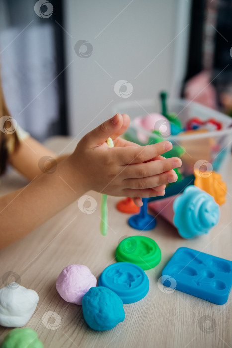 Скачать Маленькая девочка лепит фигурки из цветного воздушного пластилина, теста для лепки. Увлечения для детского творчества, развивающие занятия, развитие мелкой моторики рук. фотосток Ozero