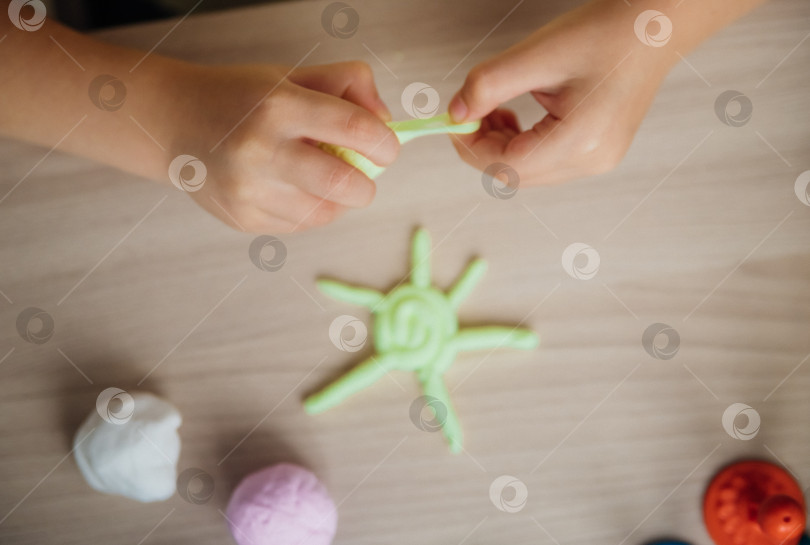 Скачать Маленькая девочка лепит фигурки из цветного воздушного пластилина, теста для лепки. Увлечения для детского творчества, развивающие занятия, развитие мелкой моторики рук. фотосток Ozero