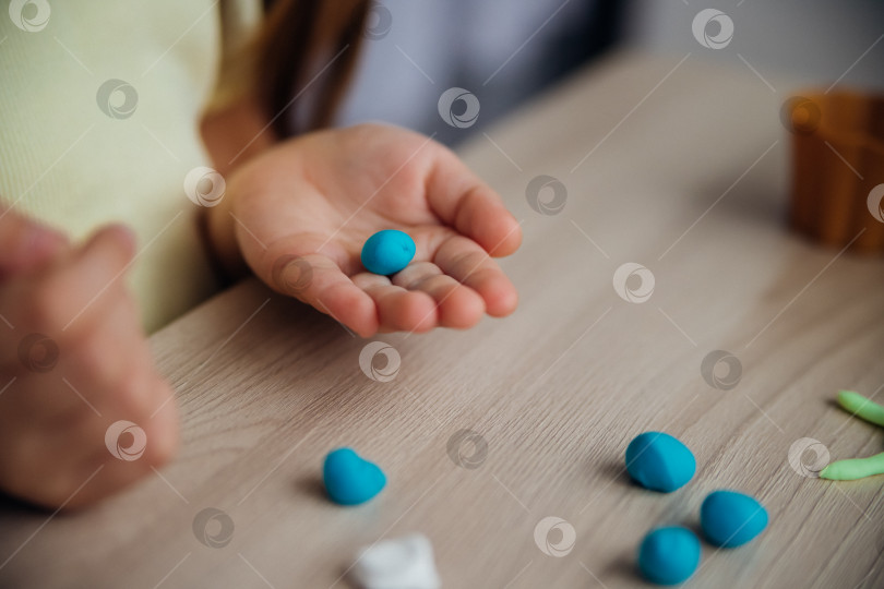 Скачать Маленькая девочка лепит фигурки из цветного воздушного пластилина, теста для лепки. Увлечения для детского творчества, развивающие занятия, развитие мелкой моторики рук. фотосток Ozero