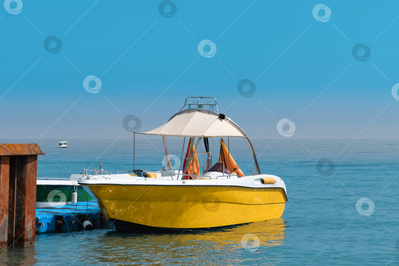Скачать Лодка у причала возле спокойной воды на фоне ясного неба в полдень фотосток Ozero