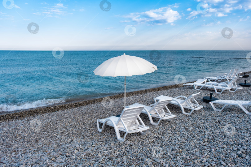 Скачать В ясный день на пляже у воды расставлены шезлонги и зонтики фотосток Ozero