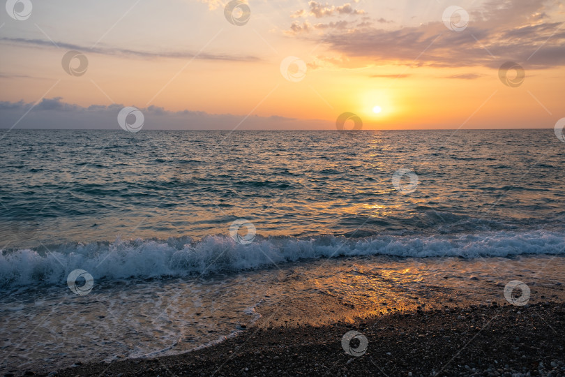 Скачать Вечером золотое солнце садится над океанскими волнами на тихом пляже, создавая теплое свечение на воде, когда день переходит в ночь фотосток Ozero