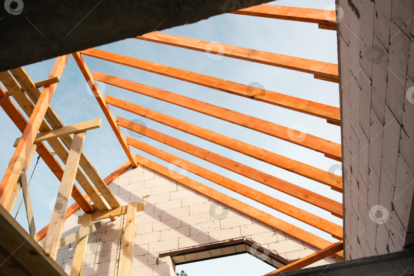 Скачать Внутренний вид крыши показывает установку новых деревянных стропил и лаг, современное строительство дома, поддерживаемое страховкой и ипотечным кредитом. фотосток Ozero