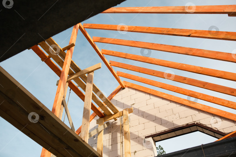 Скачать Современная мансардная крыша, деревянные лаги и стропильная система почти готовы, будущий дом финансируется за счет банковской ипотеки, страховой полис покрывает риски. фотосток Ozero