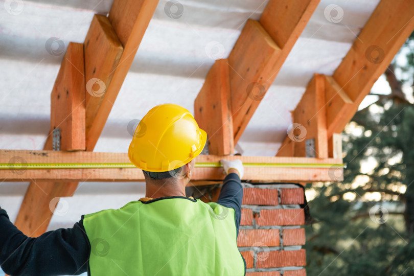 Скачать Мастер-строитель обеспечивает устойчивость потолочного бруса при монтаже кровельных лаг, тщательном расположении вручную, а также при строительстве дома и столярных работах. фотосток Ozero