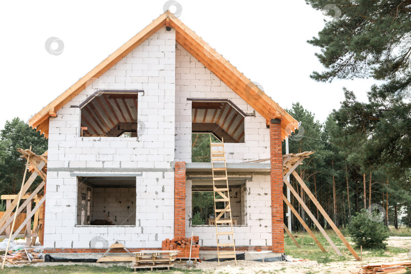 Скачать Новый дом в европейском стиле, строительная площадка с открытыми стропилами и лагами на крыше, поэтапный монтаж системы stropil, вид при дневном свете. фотосток Ozero