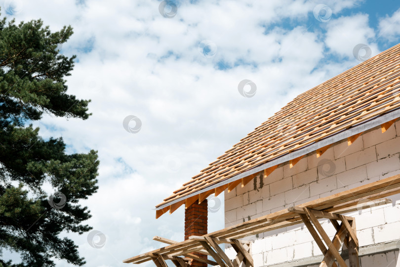 Скачать Современный дом из белых блоков с видимыми выступами древесины, система stropil завершает форму, светлый фасад, европейская технология кровли на участке. фотосток Ozero