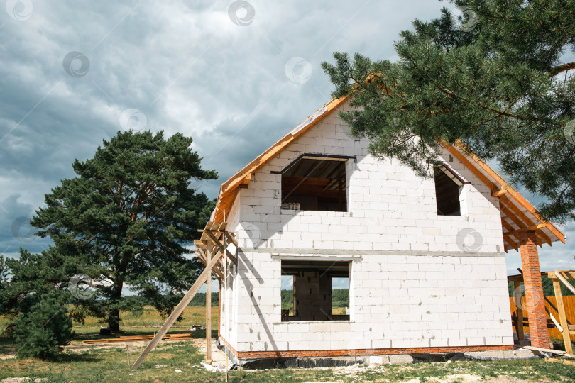 Скачать Современный евро-дом, поэтапный монтаж деревянных лаг и стропильного каркаса, белый фасад с видимым ходом строительства. фотосток Ozero