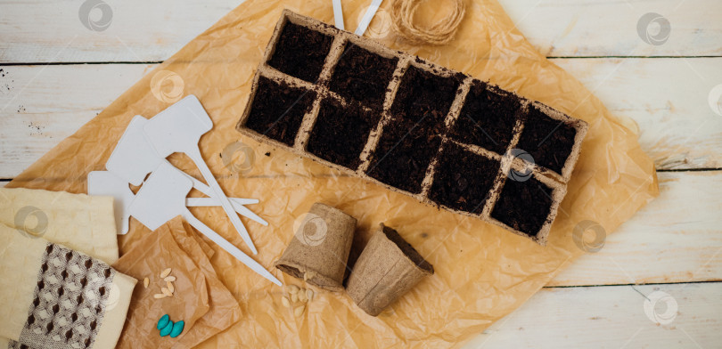 Скачать Вид сверху на семена и ячейки с почвой на деревянном фоне. Выращивание рассады в торфяных стаканчиках. Концепция весеннего озеленения дома. фотосток Ozero