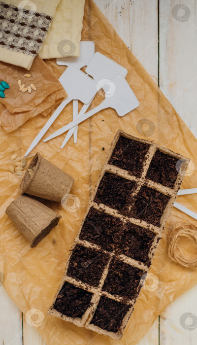 Скачать Вид сверху на семена и ячейки с почвой на деревянном фоне. Выращивание рассады в торфяных стаканчиках. Концепция весеннего озеленения дома. фотосток Ozero
