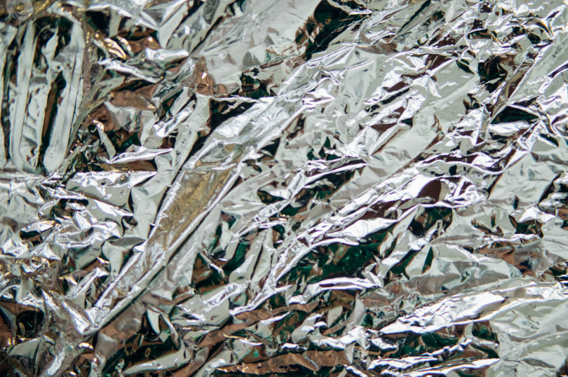 Скачать Смятая серебряная фольга. Фон переливается всеми цветами радуги. фотосток Ozero