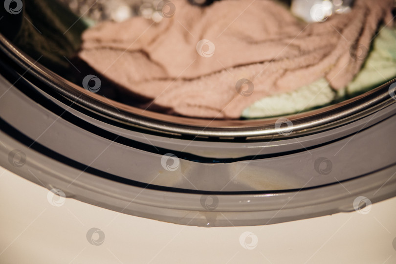 Скачать Резиновый бортик на дверце стиральной машины крупным планом. Влажный бортик после стирки внутри белья. фотосток Ozero