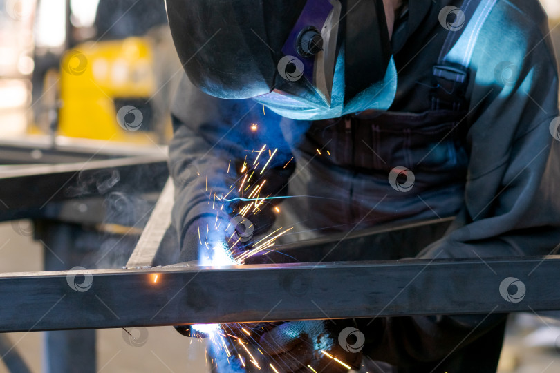 Скачать Крупный план сварщика, работающего над металлической трубой, с яркими искрами и дымом фотосток Ozero