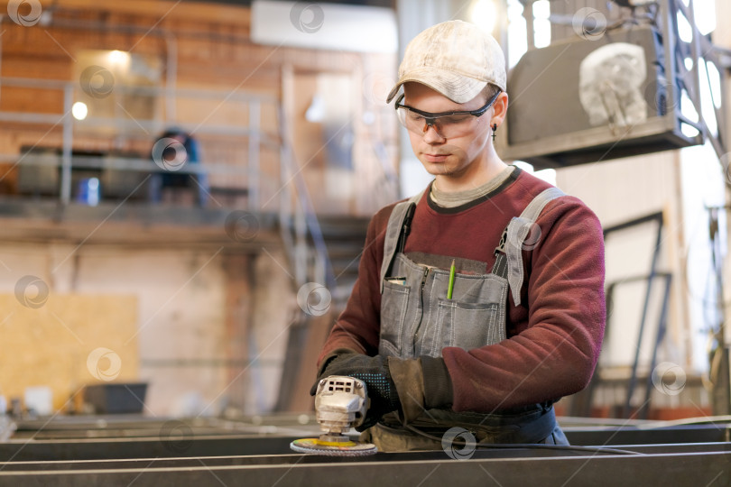 Скачать Целеустремленный Молодой слесарь, работающий со шлифовальным инструментом фотосток Ozero