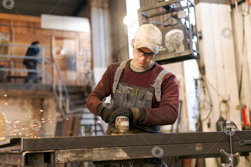 Скачать Молодой заводской рабочий, шлифующий металл так, что летят искры фотосток Ozero